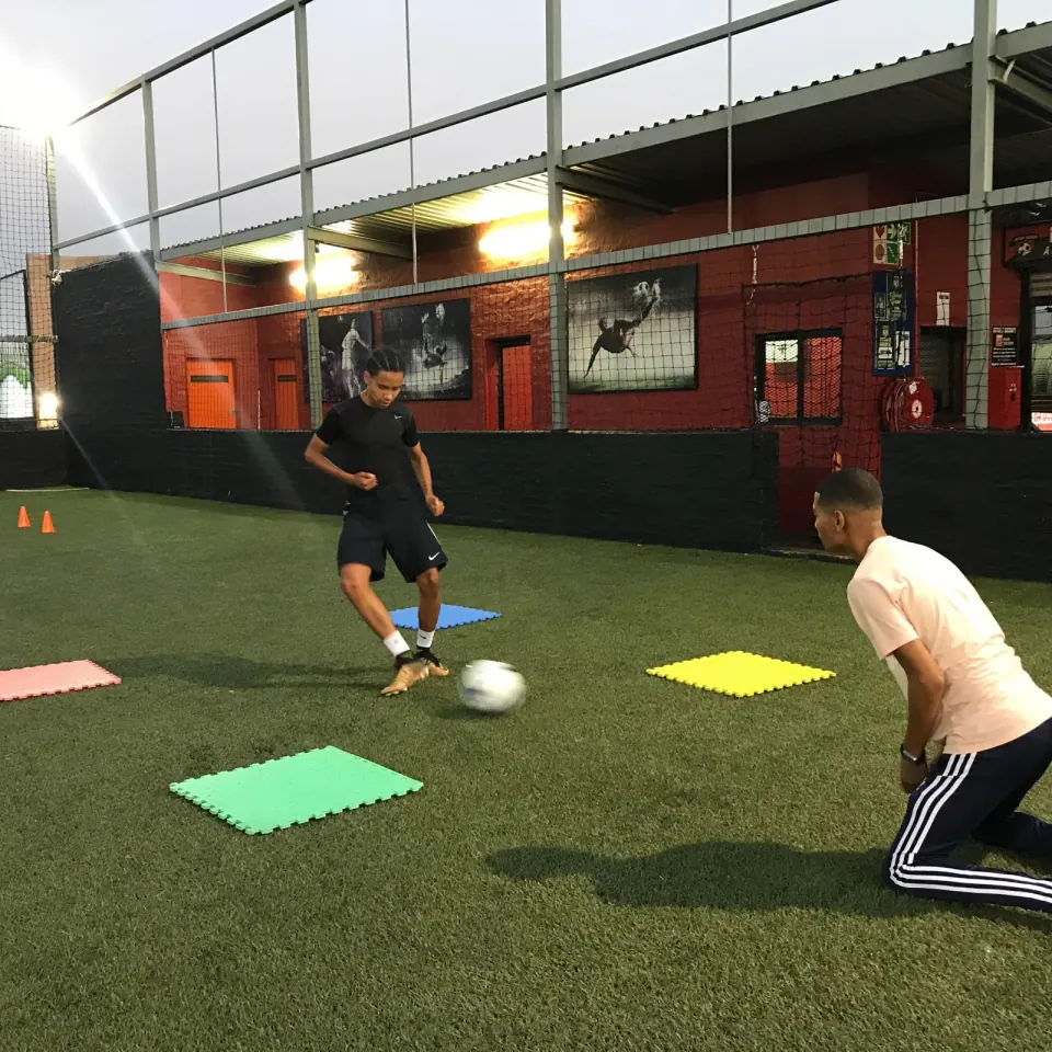 A coach and young player working on ball control